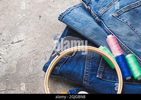 Jeans with hoop and threads on grunge background, closeup Stock Photo