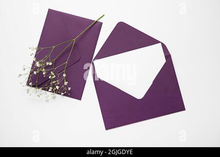 Envelopes with blank card and flowers on white background Stock Photo