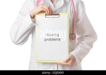Female doctor holding clipboard with text HEARING PROBLEMS on white background Stock Photo