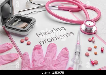 Clipboard with text HEARING PROBLEMS, stethoscope and gloves on white background Stock Photo