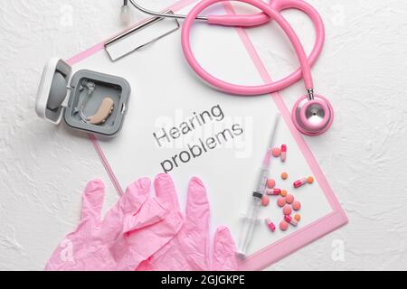 Clipboard with text HEARING PROBLEMS, stethoscope and gloves on white background Stock Photo