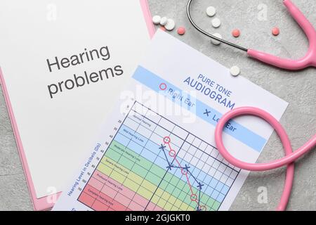 Clipboard with text HEARING PROBLEMS, stethoscope and audiogram on light background Stock Photo