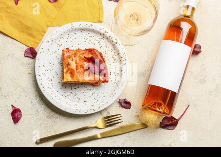 Delicious lasagna with tomato sauce in plate, cutlery and bottle of wine on light table Stock Photo