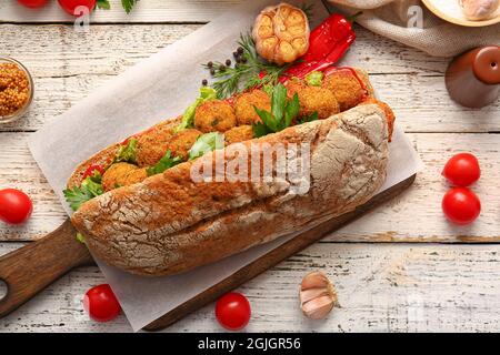 Board with bread and tasty cod cutlets on light wooden background Stock Photo