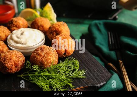 Board with tasty cod cutlets and sauce on table, closeup Stock Photo