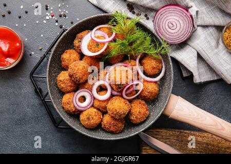 Frying pan with tasty cod cutlets and sauce on dark background Stock Photo