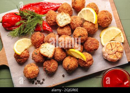 Board with tasty cod cutlets and sauce on color wooden background Stock Photo