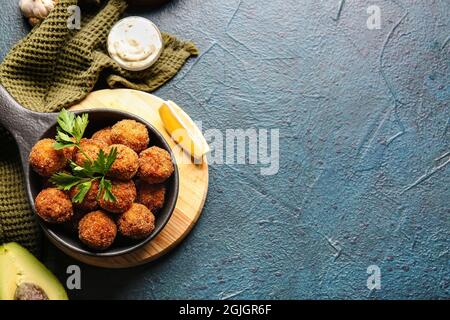 Frying pan with tasty cod cutlets and sauce on dark background Stock Photo