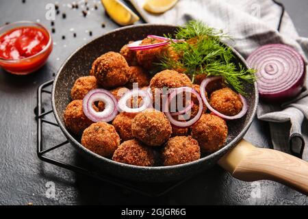 Frying pan with tasty cod cutlets and sauce on dark background, closeup Stock Photo