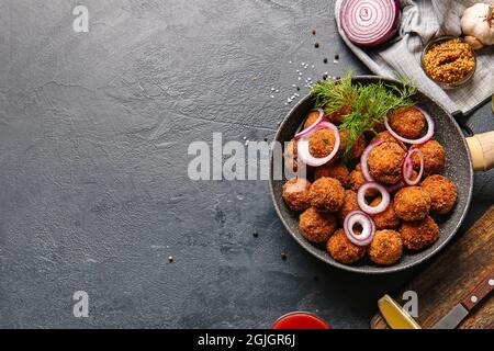 Frying pan with tasty cod cutlets on dark background Stock Photo