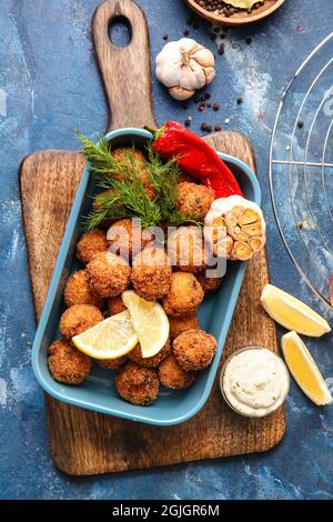 Baking dish with tasty cod cutlets, sauce and spices on color background Stock Photo