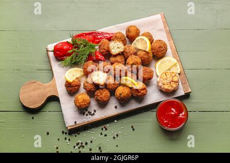 Board with tasty cod cutlets and sauce on color wooden background Stock Photo