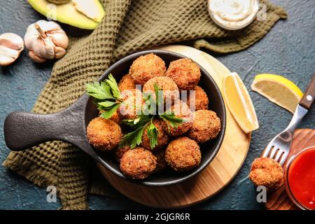 Frying pan with tasty cod cutlets and sauces on dark background Stock Photo