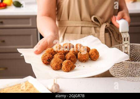 Woman holding plate with cod cutlets in kitchen, closeup Stock Photo