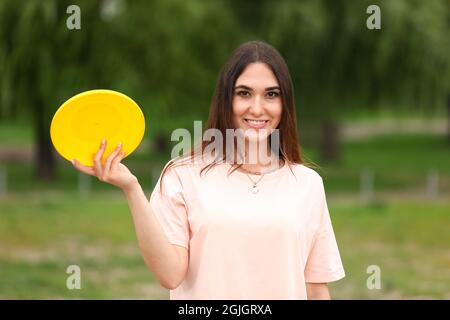 Beautiful young woman playing frisbee outdoors Stock Photo