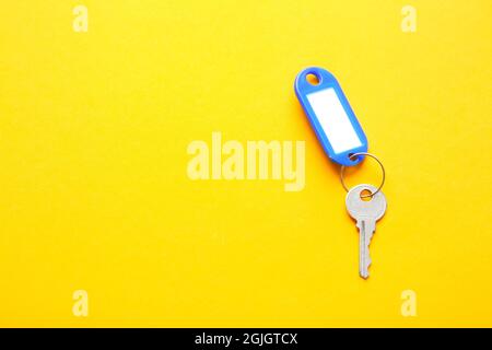 Plastic tag with key on color background Stock Photo
