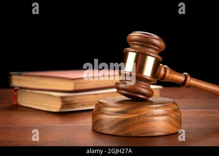 A gavel sits in front of a law book to infer research is needed for a defense and to build a case. Stock Photo