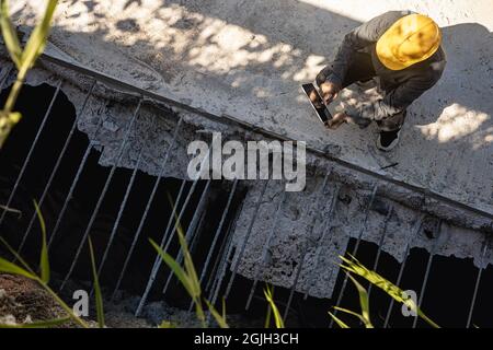 architect or civil engineer with hardhat on construction site checking schedule on tablet computer Stock Photo