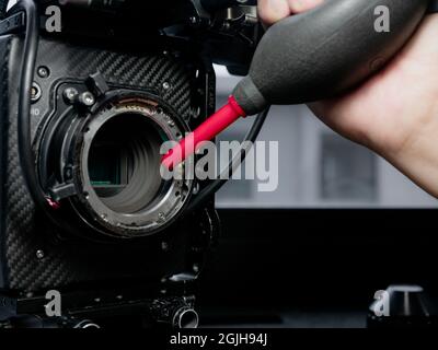 Close Up human hand using a rubber inflator o blow dust and clean the sensor glass of the movie camera. Stock Photo