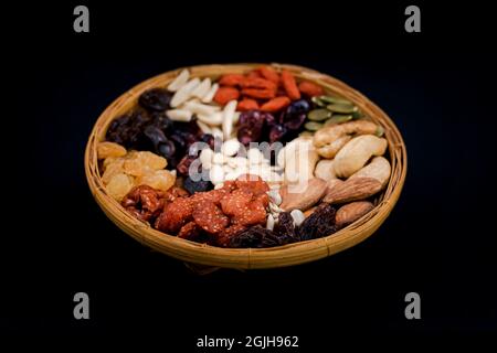 Group of various types of dried fruits and dried on a bamboo tray on black background. Stock Photo
