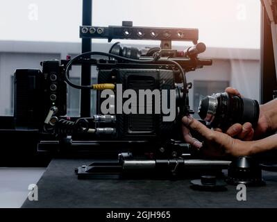 Close Up human hand inserting the cinema lens into a movie camera mount. Stock Photo