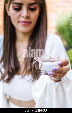 Young mexican woman holding a lit candle for holistic therapy in Latin America Stock Photo