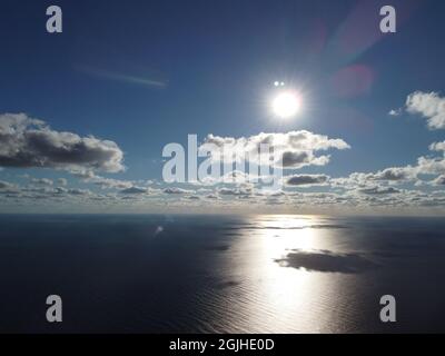 Abstract aerial nature summer ocean sunset sea and sky background. Small waves on clear water surface in motion blur with bokeh lights from sunrise Stock Photo