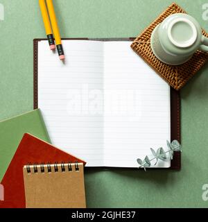 Open notebook, coffee cup, pencil on green background. top view, copy space. workspace, study concept Stock Photo