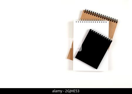 Three blank notepads on a spiral stacked in a stack on a white background. Notebooks with white, black and recycled sheets. Education, office. Stock Photo