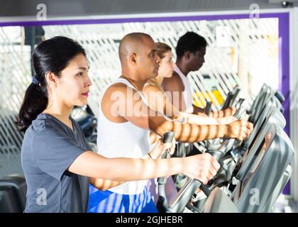 People having running elliptical trainer class in club Stock Photo