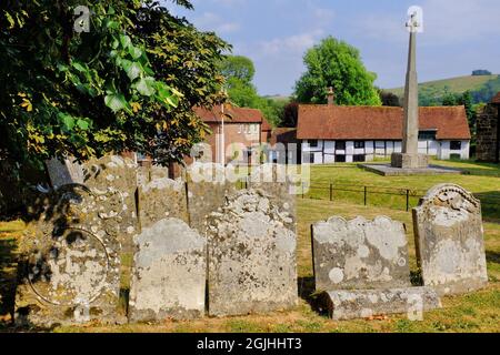 Gravestones in graveyard of Church of St Mary and St Gabriel, war memorial and half timbered cottage in South Harting, West Sussex, England Stock Photo