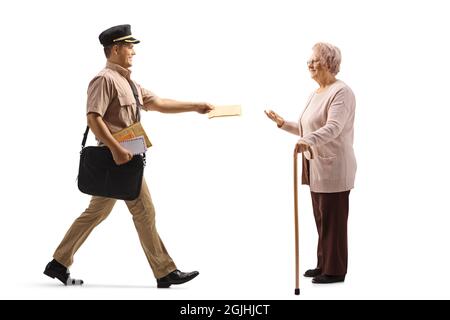 Full length profile shot of a mailman delivering a letter to an elderly lady with a walking cane isolated on white background Stock Photo