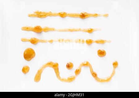 From above of assorted straight and curved lines and spots of sweet apricot jam on white table Stock Photo