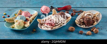 High angle of assorted banana split desserts with balls of ice cream served on plates in row on blue wooden background Stock Photo