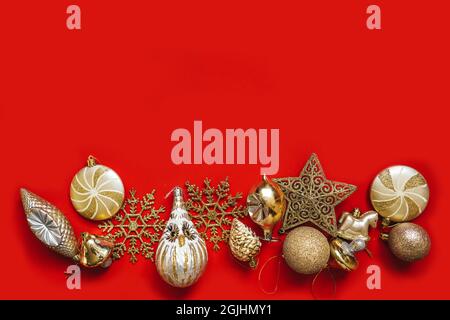 Collection of golden Christmas baubles viewed from above on red background. Copy space. Stock Photo