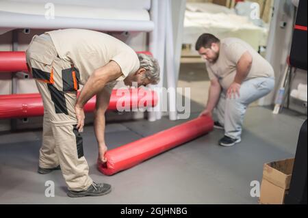Technician worker operator changes the paper roll on large premium industrial printer and plotter machine in digital printshop office Stock Photo