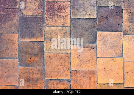 Orange brown purple old shabby worn out floor tiles with damages cracks dirt caverns potholes and paint stains. Art design background texture. Stock Photo