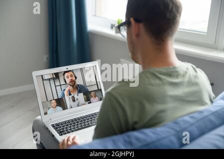 Group of diverse multiracial people on the laptop screen, a young man is talking with colleagues, employees online. Video conference, brainstorm, webinar concept Stock Photo