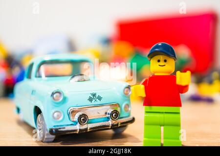 POZNAN, POLAND - Feb 15, 2019: Lego man figurine standing next to his parked old time car. Proud owner of his vintage vehicle. Stock Photo