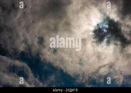 Sun obscured by clouds on the blue sky | Dramatic sky with sun shining through white and dark clouds Stock Photo