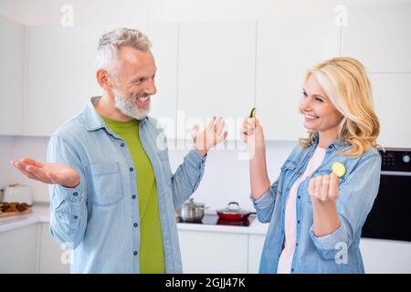 Photo of happy smiling cheerful married couple spouses fooling around wife hold slice of cucumber enjoying weekend Stock Photo