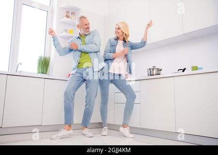 Photo of charming carefree aged couple wear denim shirt smiling dancing indoors house room Stock Photo