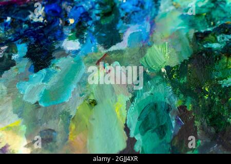 Blue turquoise oil paint close-up. Blurry multicolored background. The artist's professional paints are in selective focus. The concept of creativity Stock Photo