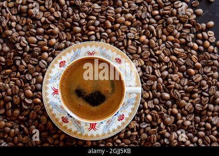 coffee beans in the background and a cup of frothy turkish coffee on top. Selective Focus. Stock Photo