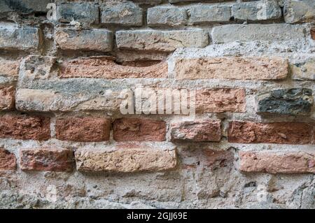 Grey white black red orange old vintage brick wall background. Rustic cemented brick house wall texture with grunge surface. Shabby Building Facade With Damaged Plaster Stock Photo