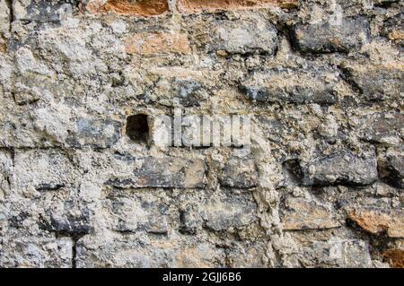 Grey white black red orange old vintage brick wall background. Rustic cemented brick house wall texture with grunge surface. Shabby Building Facade With Damaged Plaster Stock Photo
