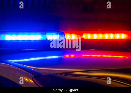 Detail of police car with lights flashing with red and blue colors on blurred background of city street Stock Photo