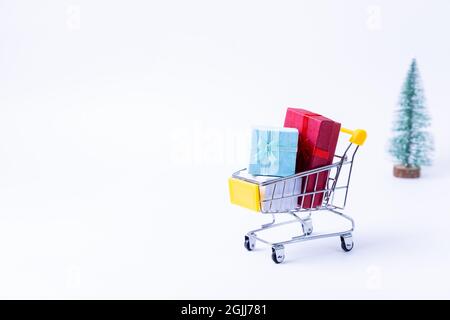 Miniature cart with gifts on a white background. Christmas and New Year shopping concept. Close-up. Stock Photo
