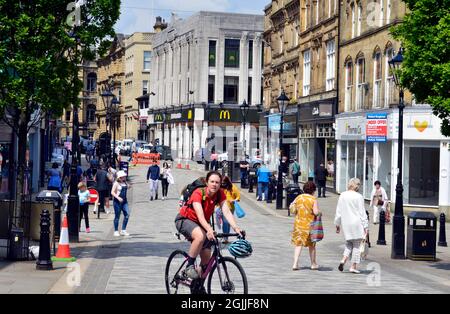HALIFAX. WEST YORKSHIRE. ENGLAND. 05-29-21. Cornmarket in the town centre. Shoppers and cyclist.
