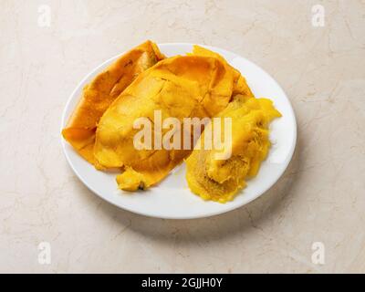 Yellow mango skin and large pit on a whte plate over kitchen table. Fresh ripe mango seed and peelings close-up. Household biodegradable kitchen waste Stock Photo